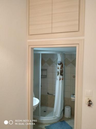 un vestido colgando de una puerta en un baño en Cosi Apartment en Paralia Dionysiou