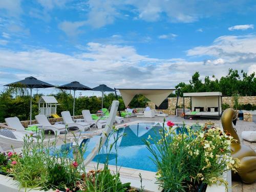 a swimming pool with white chairs and umbrellas at Villa Green Diamond - Private Heated Pool in Platanes