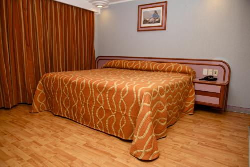 a bedroom with a bed with an orange comforter at Hotel Cuba in Mexico City