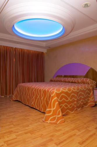 a bedroom with a bed with a blue light on the ceiling at Hotel Cuba in Mexico City