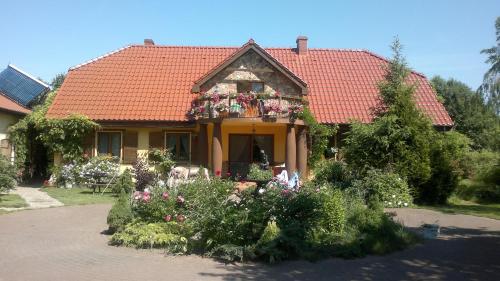 a house with a red roof with flowers on it at Dworska Zagroda in Korytowo