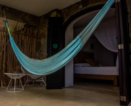 a hammock in a room with a bed at El Alquimista Yoga Spa in Zipolite