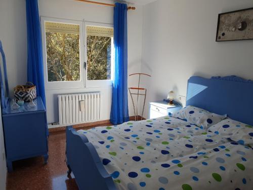 Un dormitorio con una cama azul con cortinas azules y una ventana en Ca la Rita, en Castellfollit de la Roca