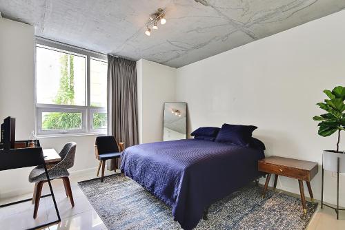 1 dormitorio con cama con colcha púrpura y escritorio en Miami Midtown Luxury Apartment, en Miami
