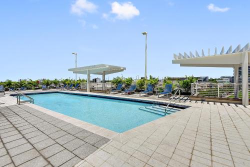 a large swimming pool with chairs and a umbrella at Miami Midtown Luxury Apartment in Miami