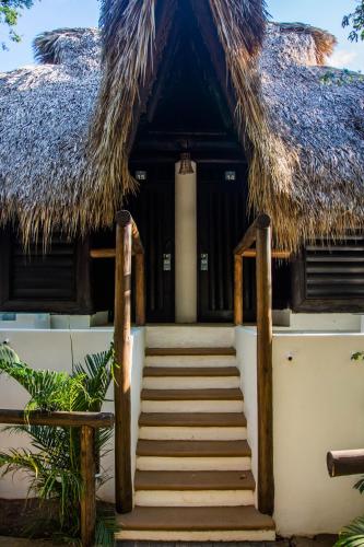 a staircase leading to a building with a thatched roof at El Alquimista Yoga Spa in Zipolite