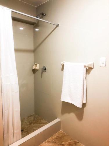 a bathroom with a shower and a white towel at Hawka Inka Hostal - Cusco in Cusco
