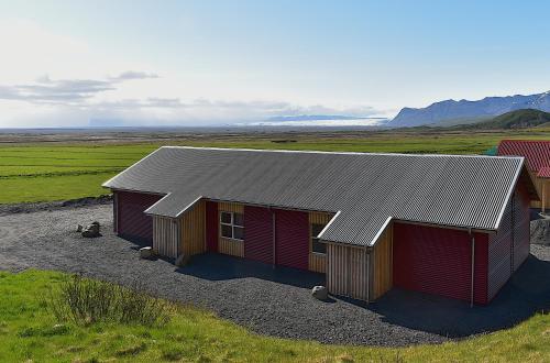 a red building with a gray roof in a field at The Potato Storage in Svínafell