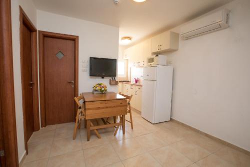 a small kitchen with a table and a white refrigerator at Hadass Desert Inn in Dimona