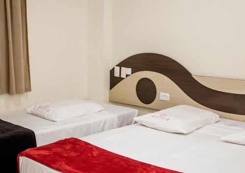 two beds in a room with white sheets and red blanket at Alkimia Hotel in Campo Grande