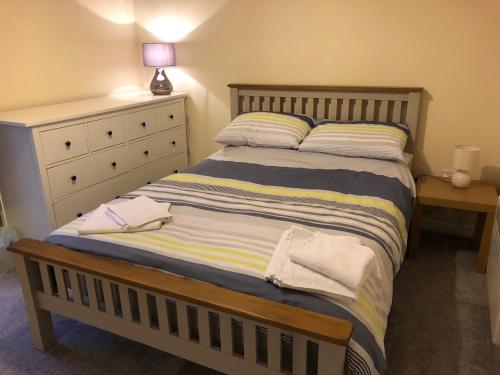 a bedroom with a large bed with a dresser and a lamp at 41 Larchwood Drive Holiday Home in Inverness