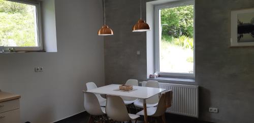 a white table and chairs in a kitchen with two windows at Apartament przy Mickiewicza in Stronie Śląskie