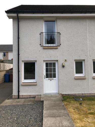 a white house with a white door and a balcony at 41 Larchwood Drive Holiday Home in Inverness