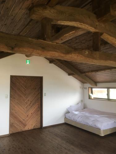 sypialnia z łóżkiem i drewnianym sufitem w obiekcie SOCKET w mieście Minami Aso