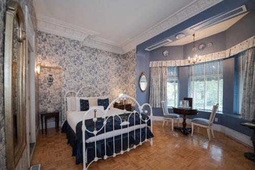 Manoir Sherbrooke في مونتريال: غرفة نوم بسرير وطاولة وكراسي