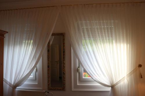a room with white curtains and a mirror at Hotel & Restaurant Pension Bei der Post in Bacharach