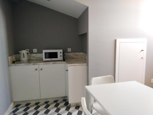 a kitchen with white cabinets and a white microwave at ALM SANTA LUZIA in Guimarães