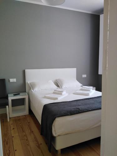 a bedroom with a large bed with white sheets at ALM SANTA LUZIA in Guimarães
