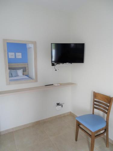 a room with a chair and a television on a wall at Proteas Mare Suites in Protaras