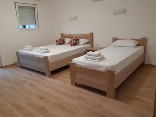 two beds in a room with wooden floors at Apartmani Marina Kopitovic in Petrovac na Moru