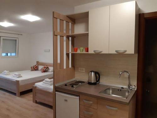 a kitchen with a sink and a bed in a room at Apartmani Marina Kopitovic in Petrovac na Moru
