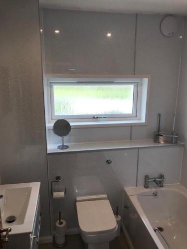 a bathroom with a toilet and a sink and a window at Heb Holiday, Self Catering Accommodation, Isle of Benbecula in Gramisdale