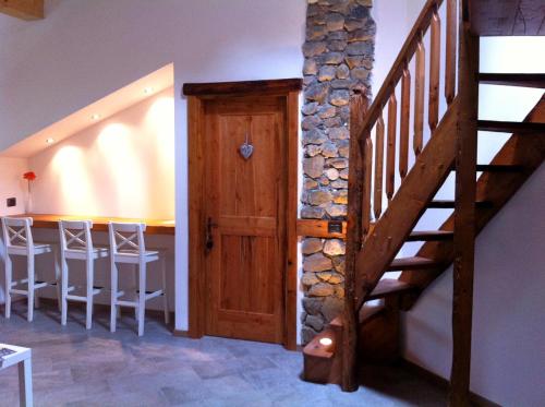 a wooden staircase in a room with a stone wall at Mortirolo in Mazzo di Valtellina