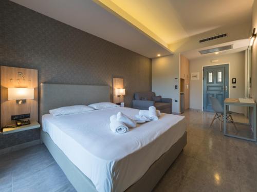 a bedroom with a large white bed with towels on it at Paradise Resort in Finikounta