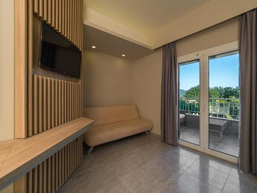 a room with a couch and a tv and a balcony at Paradise Resort in Finikounta