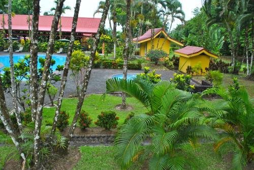 a resort with a yellow house and a pool at Hotel Arenal Country Inn in Fortuna