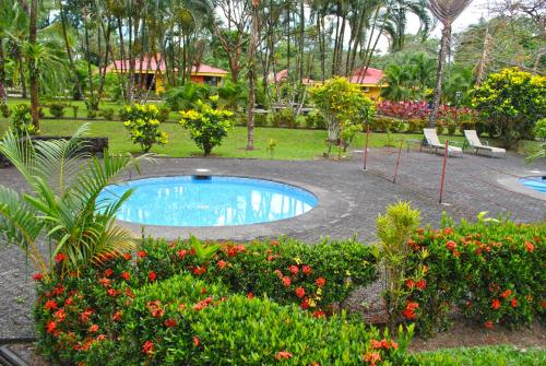 a swimming pool in a garden with flowers and plants at Hotel Arenal Country Inn in Fortuna