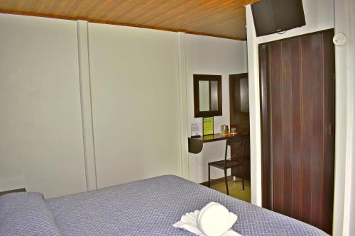 a bedroom with a bed with a hat on it at Hotel Arenal Country Inn in Fortuna