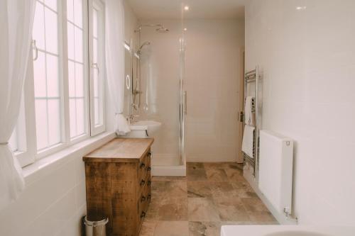 La salle de bains est pourvue d'un lavabo, d'une douche et d'une table en bois. dans l'établissement Owners Residence, à Wales