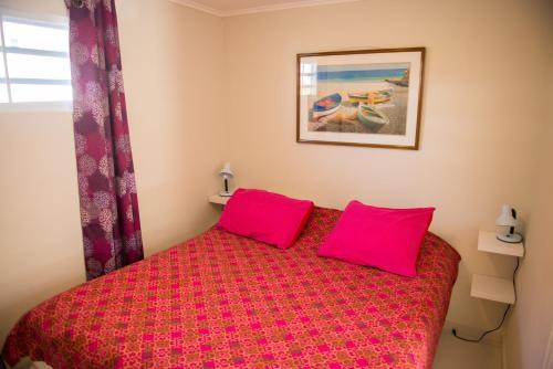 een slaapkamer met een rood bed met 2 roze kussens bij Jan Thiel Garden Apartement in Jan Thiel