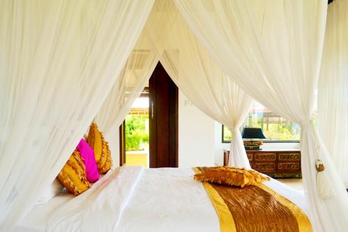 a bedroom with a white bed with white curtains at Villa Bidadari Kutuh Nusa Dua in Nusa Dua
