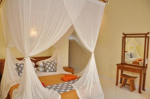 a bedroom with a canopy bed with white drapes at Nick's Homestay in Ubud