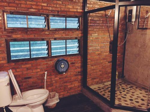 a brick bathroom with a shower and a toilet at Monsamkien Farmstay in Phayao