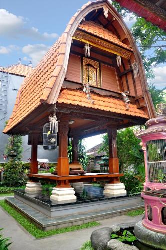 a small house with a roof in a garden at Nick's Homestay in Ubud