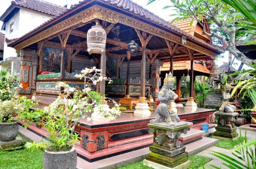 a small house with a statue in a garden at Nick's Homestay in Ubud