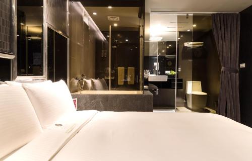 a bedroom with a white bed and a bathroom at Vendome East Inn in Taipei