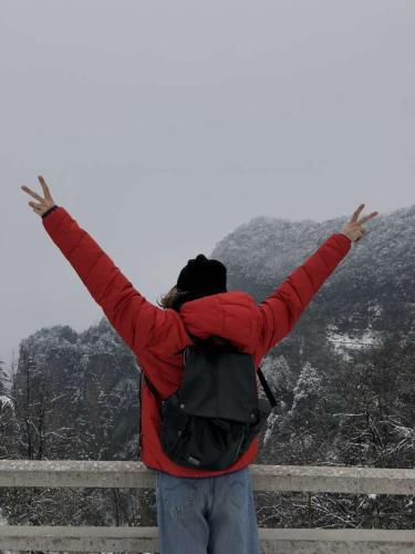 a person in a red jacket standing with their arms up at Riverside Peak Lodge Zhangjiajie Wulingyuan National Park in Zhangjiajie