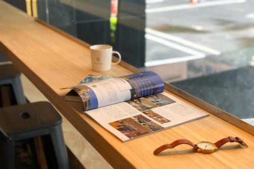 a table with a book and a cup and a pair of glasses at Talmud Hotel Taichung in Taichung