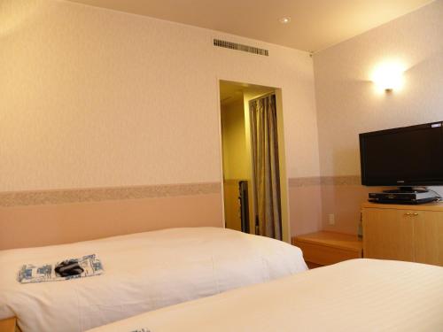 a hotel room with two beds and a flat screen tv at Hotel Benex Yonezawa in Yonezawa