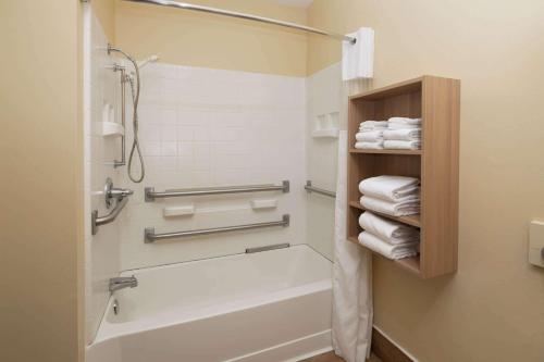 a bathroom with a tub and a shower with towels at Microtel Inn & Suites by Wyndham Florence in Florence