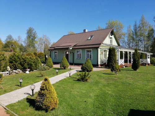 a house with a green house with a yard at Rähni Guesthouse Lake Peipsi in Vilusi