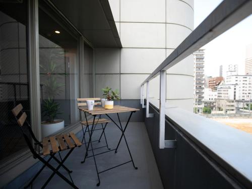 uma varanda com uma mesa e cadeiras num edifício em BIG ROOM GUEST HOUSE em Osaka