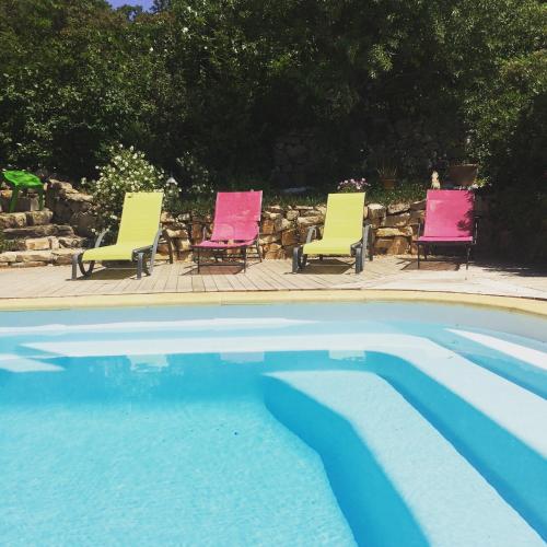 three chairs and a swimming pool with pink and yellow at l'Oustaou B&B Piscine & Spa in Besse-sur-Issole