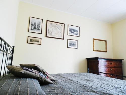 a bedroom with a bed and framed pictures on the wall at Villa Albonico in Laglio