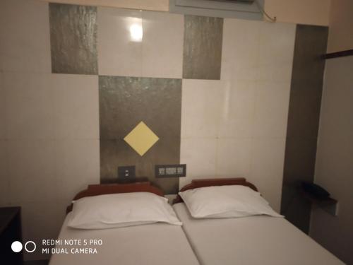 a small bedroom with two beds in it at Krishna Lodge in Tiruchchirāppalli