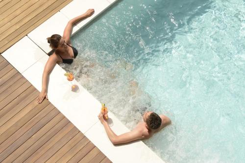 a man and a woman in a swimming pool at Corona Dolomites Hotel in Andalo